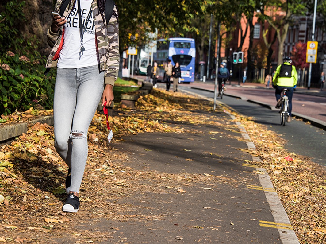 A woman walking on a city centre pavement in autumn